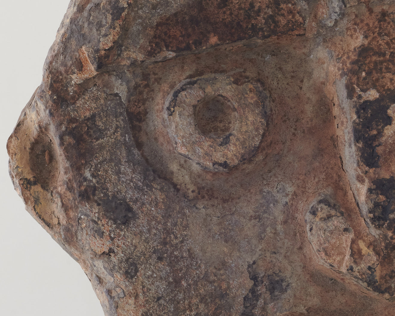 Carved relief stone face on stand